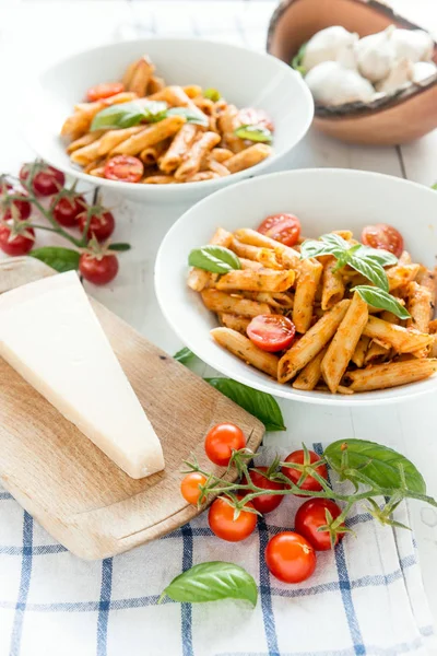 Ahşap beyaz masa üzerinde Fesleğenli domates soslu penne makarna