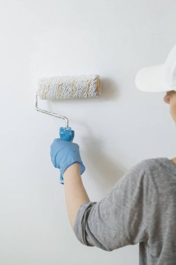 Kadın ressam beyaz bir rulo ile duvar boyaları.