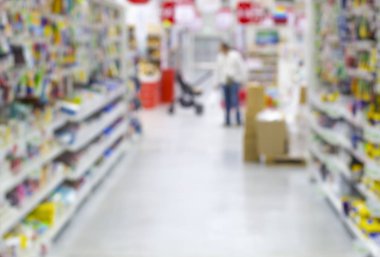 Renkli rafları ve tanınmayan müşterileri olan soyut bulanık süpermarket koridoru