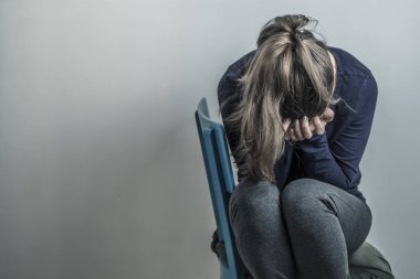 Bir kadınla depresyon. Üzgün bir kız bir odada oturuyor. Boşluğu kopyala.