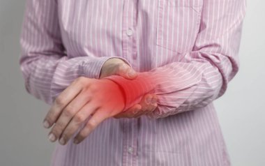 Kadın ağrıyan bileğini tutuyor. Bilek eklemi kadını rahatsız ediyor. İltihaplı el.