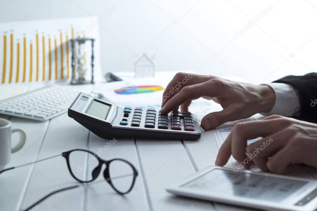 A sales manager counts on a calculator looking into infographics. Hands accountant prepare a report, tax time.