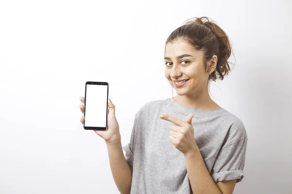 Gülümseyen Hintli bir kızın portresi akıllı telefonun beyaz ekranını işaret ediyor..