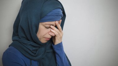 Başörtülü Müslüman bir kadın elleriyle yüzünü kapatarak ağlar. Arap kız depresyonda, üzgün. Boşluğu kopyala.