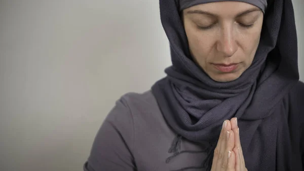 A Muslim woman prays in a hijab. Copy space.