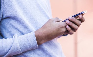 Siyah bir adamın elinde bir cep telefonu yakın çekim. Smartphone kullanır. 