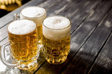 Bar masasında taze köpüklü bira kupaları. 