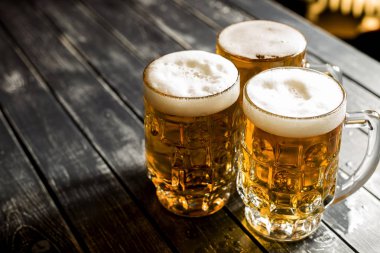Bar masasında taze köpüklü bira kupaları. 