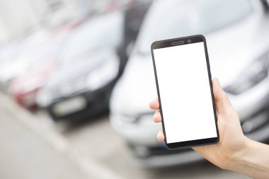 Araçların arka planda beyaz bir ekran ile eldeki smartphone. Cep telefonundan taksi sipariş etme. 