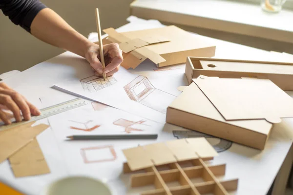 Eller tasarımcısı kağıt ambalaj bir kroki çizer. Ekolojik kutuların yaratıcı gelişimi.