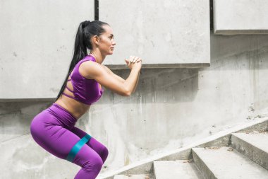 Squats. Direnç bandı sportif genç kadın ganimet bant germe kayışı ile squat egzersiz yapıyor. Fitness kadın trenler lastik kalça kasları.