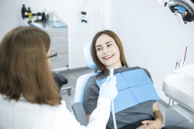 Smiling girl in the dental chair at the reception at the dentist clipart