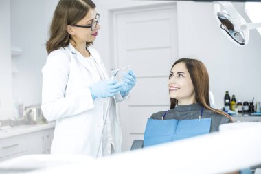 Gülümseyen kız doktor diş sandalyesinde otururken diş davranır. 