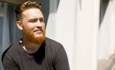 Sakallı çekici kızıl saçlı bir adamın portresi. Gülümseyen bir erkek yüzünün yakın çekim. 