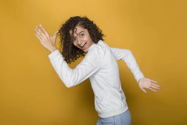 An excited black young Afro woman mixed race runs in the studio.