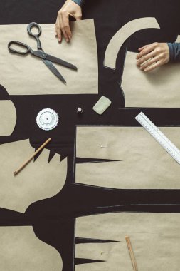 Terzi stüdyodaki kumaşın kalıbını belirler. Kesici iş yerindeki şablonu özetliyor.. 