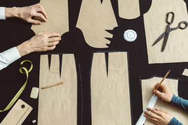 Terzi stüdyodaki kumaşın kalıbını belirler. Kesici iş yerindeki şablonu özetliyor..