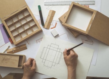 Geliştirme tasarımı çizim paketleme. Karton kutular yapan yaratıcı bir kişinin masaüstü.