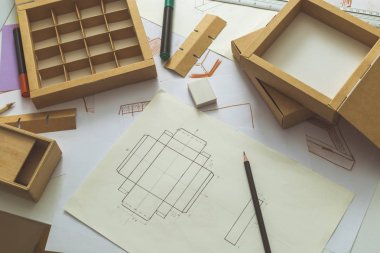 Geliştirme tasarımı çizim paketleme. Karton kutular yapan yaratıcı bir kişinin masaüstü.