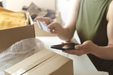 Kadın kredi kartıyla ödemek için akıllı telefon kullanıyor.