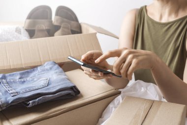 Bir kadın içinde mallar olan bir paket kutusu aldı. Çevrimiçi akıllı telefon alışverişi.