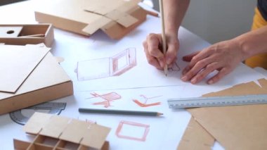  Paketleme tasarımı taslağının geliştirilmesi. Tasarımcı karton kutu yapmak için bir maket çizer. 