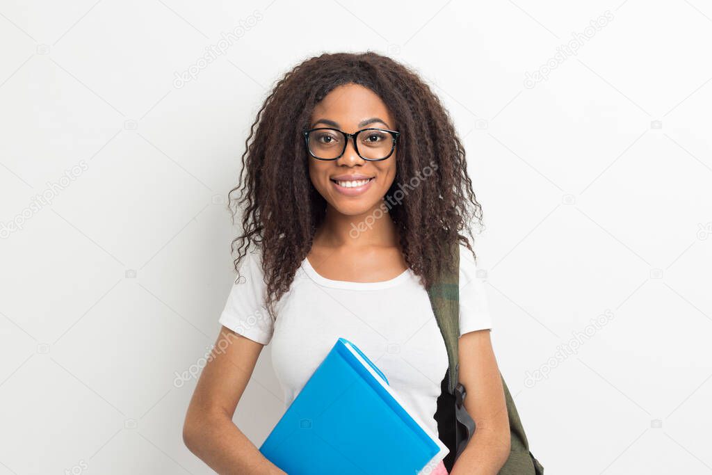 Portrait of a smiling African American female student girl in glasses. Happy and successful black young woman with books.