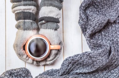 Eldivenli kadının elleri soğuktan korunmak için bir fincan sıcak içecek, çay ya da kahve tutuyor. Kış ve Noel zamanı kavramı.
