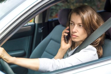 Kadın sürücü arabada otururken telefonla konuşuyor..