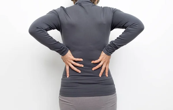 Kidney pain in a woman. The girl holds on to her sore back.