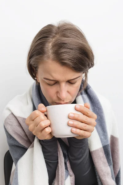 A sick woman with a cold is drinking tea.