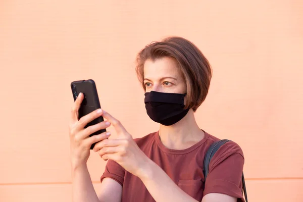 A woman in a medical mask uses the phone.