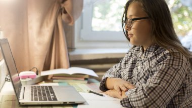 Liseli kız evde otururken dizüstü bilgisayar kullanmayı öğreniyor. Karantina sırasında uzak bir ders. Dijital aygıtla çalış.