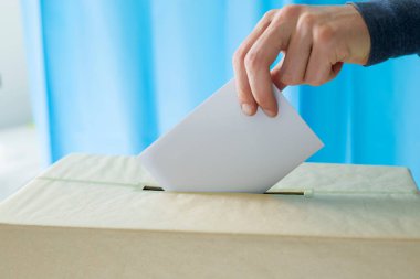 Seçim ya da referandum sırasında sandık merkezinde oy kullanmak için oy pusulası tutan bir adam.