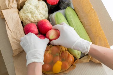 Gönüllü bir kadının elleri yiyecekleri bir kutuya koyar. Bakkaliye teslimatı. İhtiyacı olanlara yardım etmek..