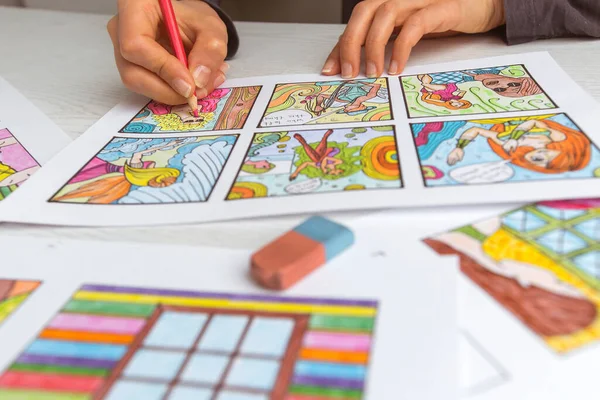 An animator painter draws a color storyboard for a comic book or movie. An illustrator seated at his desk creates a storyboard for a cartoon.