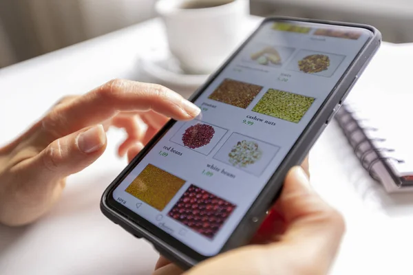 Online shopping. Woman buys food in an online store choosing on a smartphone.