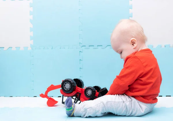 Niedliches Baby spielt mit bunten Regenbogen-Spielzeug-Pyramide sitzt auf Spielmatte in weißen sonnigen Schlafzimmer. Spielzeug für kleine Kinder. Interieur für kleine Knabenkinder. Kind mit Lernspielzeug. Frühe Entwicklung. — Stockfoto