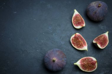Taze incir. Gıda Fotoğrafçılık. Bütün ve dilimlenmiş incir bir dikdörtgen içinde yazıtlı karanlık bir arka plan üzerinde yaratıcı şeması. Kopya alanı