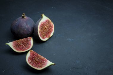 Taze incir. Gıda Fotoğrafçılık. Bütün ve dilimlenmiş incir bir dikdörtgen içinde yazıtlı karanlık bir arka plan üzerinde yaratıcı şeması. Kopya alanı