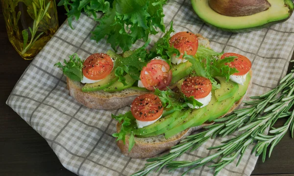 Avocado toast, cherry tomato on wooden background. Breakfast with toast avocado, vegetarian food, healthy diet concept.