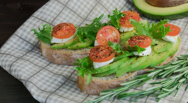 Avocado toast, cherry tomato on wooden background. Breakfast with toast avocado, vegetarian food, healthy diet concept.