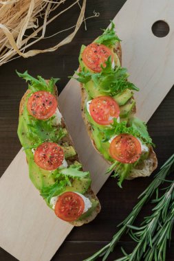 Avokado tost, kiraz domates ahşap arka plan üzerinde. Kahvaltı tost avokado, Vejetaryen gıda, sağlıklı beslenme kavramı ile.