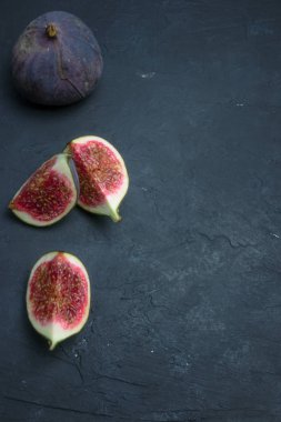 Taze incir. Gıda Fotoğrafçılık. Bütün ve dilimlenmiş incir bir dikdörtgen içinde yazıtlı karanlık bir arka plan üzerinde yaratıcı şeması. Kopya alanı
