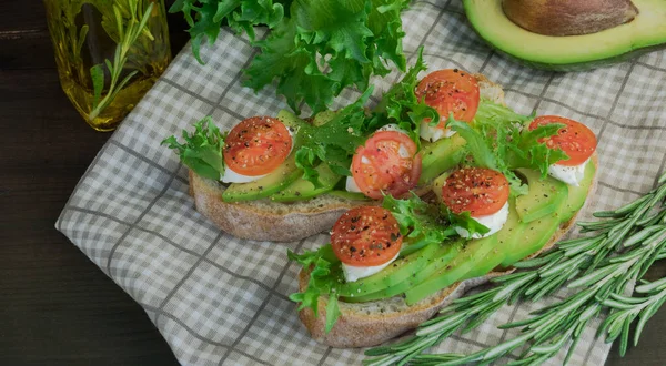 Avocado toast, cherry tomato on wooden background. Breakfast with toast avocado, vegetarian food, healthy diet concept.food