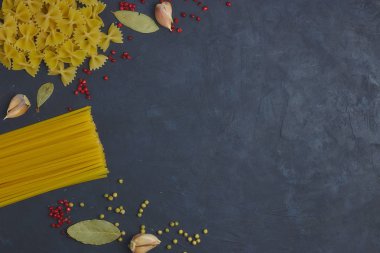 Baharat ve baharat siyah beton zemin üzerine yanındaki pişmemiş makarna çeşitli. Yukarıdan görüntüleyin. Kullanılabilir alanı kopyalayın. Ben