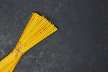 Pişmemiş makarna ile siyah arka plan beton bir ipe bağlı. kopya alanı. yukarıdan görüntülemek.