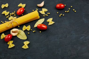 Yemek için çerçeve. Makarna malzemeler. Kiraz domates, spagetti makarna, sarımsak ve baharat bir karanlık grunge arka planda, kopya alanı, görünümü top