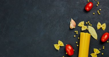 Yemek için çerçeve. Makarna malzemeler. Kiraz domates, spagetti makarna, sarımsak ve baharat bir karanlık grunge arka planda, kopya alanı, görünümü top