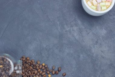 kavrulmuş kahve çekirdekleri, bir cam kavanoz beyaz fincan kahve ve hatmi ile üzerinden dökülür. kahve nesne açısal yerleşimi. karanlık beton üzerinde. yukarıdan görüntüleyin. kopya alanı.